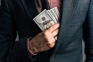 businessman with ring on his hand in suit hides American money