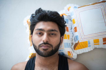 Top down portrait of an young Indian Bengali brunette man sleeping peacefully with blanket and...