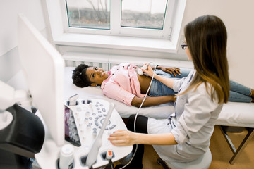 Ultrasound diagnostic of stomach on abdominal to young African woman. Doctor runs ultrasound sensor...