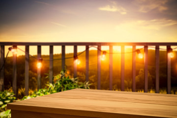Wooden board of free space for your decoration. Blurred background of balcony and ladnscape of Tuscany.Small lights and orange color of sunset time. 