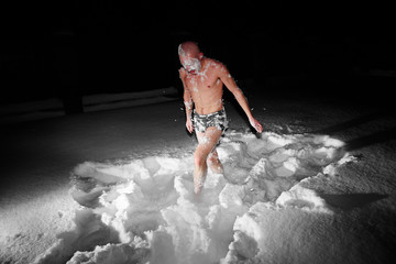 Healthy hardening. Young man dives and walks in the snow after hot sauna and bathes in cold water. Strengthening the body and spirit concept