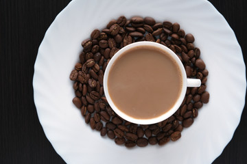 cup of coffee on a plate with coffee beans