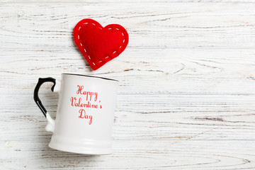 Top view of a cup and red hearts falling out from it on wooden background. Happy Valentine's Day concept