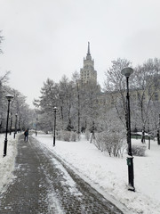 A path in a winter square against the background of a Soviet-era high-rise building.