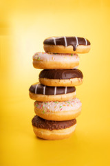 Poster with a pile of various donuts on yellow background. Sweet pastries of Fat Thursday. Doughnuts