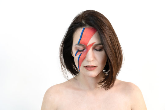 Young beautiful girl with original make-up on her face looks down. Isolated on a white background