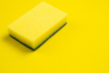 Yellow dishwasher sponge on a yellow background