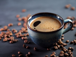 Blue Cup of fresh hot espresso coffee on a dark table with coffee beans