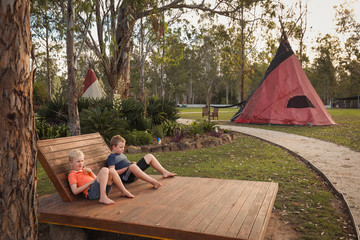 Two brothers relaxing on daybed at tipi camp ground