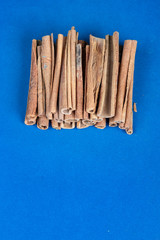 bunch of cinnamon sticks on blue background, empty space for text, ingredient for cooking