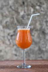 Freshly squeezed juice from tropical fruits in a glass goblet on the background of an old stone wall. Island of Zanzibar, Tanzania, Africa. Close up, copy space