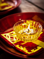 A candle in a glass cup and joss papers