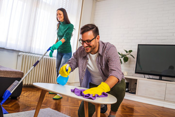 Young happy couple is cleaning their apartment.