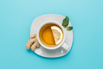 Tea cup with lemon, ginger and mint on blue background