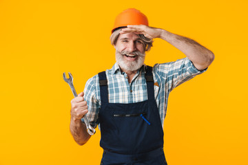 Bearded man builder in helmet holding wrench.