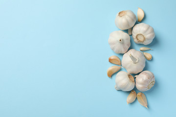 Fresh garlic bulbs, slices on blue background, top view. Space for text