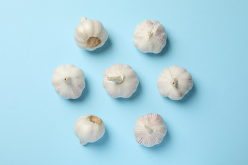 Flat lay of fresh garlic bulbs, slices on blue background, top view. Space for text