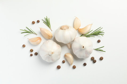 Flat lay of composition, garlic bulbs, slices, spice, parsley, rosemary on white background, top view. Space for text