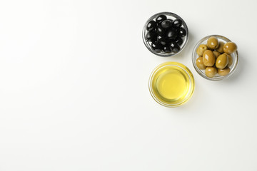 Bowls with olives and oil on white background, top view