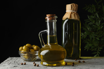 Bottle and jug with olive oil against black background, space for text