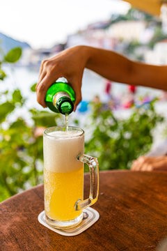 Hand filling a glass of beer on a terrace