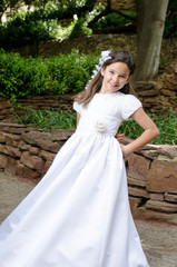 Obraz na płótnie Canvas First holy communion, beautiful girl smile while spinning in her white dress at the park.