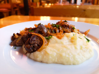 Roasted liver with onions and mashed potatoes in a restaurant.