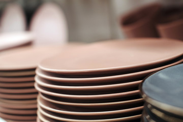 Stack of color ceramic plates in a store. Varieties of tableware. Set of kitchen plates on a store shelf.