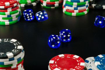 Dice and chips on black table close up