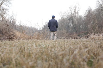 Naklejka na ściany i meble man view from behind walking alone in countryside landscape with copy space for your text