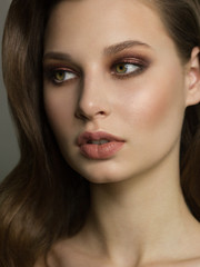 Fototapeta premium Beautiful brunet model woman face with green eyes and perfect make-up. Portrait of beauty young brunet girl with natural lips and smoky eyes, thick eyesbrow . Female face with clear skin close-up.