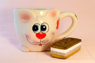 colored cup mug in the form of a hare and a cake on a pink background