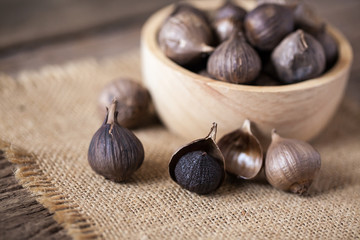 Black garlic on sack cloth and wooden table