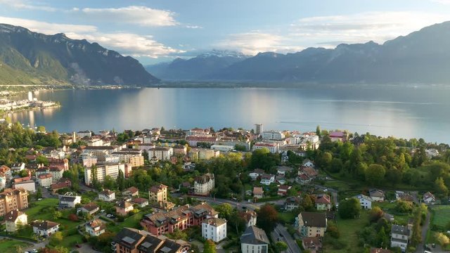 Magic hour aerial lateral shot of Switzerland Montreux with view to Lake Geneva and Snowy Mountains top