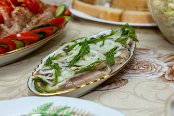 oblong oval dish with herring, onions and dill on a laid festive table