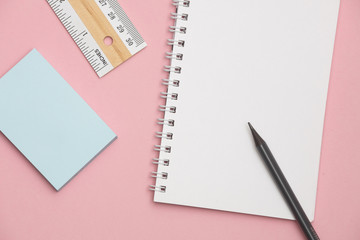 Pink office desk table with notebook and supplies.