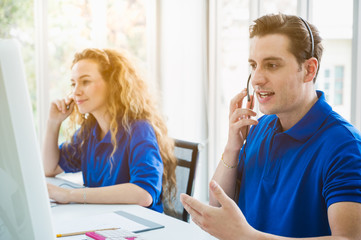 Customer support operator at work. Team Business and Delivery call center in office. Working with a headset in blue uniform.