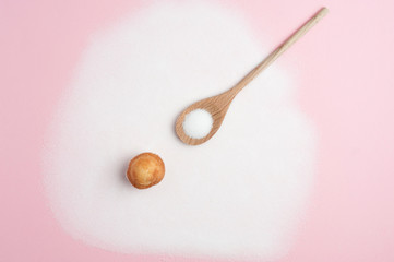 Fototapeta na wymiar Composition with sugar, wooden spoon with sugar, and cupcake, on pink background, top view