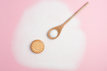 Composition with sugar, wooden spoon with sugar, and cookie, on pink background, top view