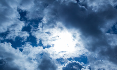 Light makes its way through beautiful large clouds against a clean blue sky