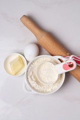 Obraz na płótnie Canvas flour, rolling pin and eggs on a white background top view