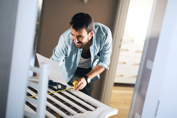 Man reading instructions for assembling baby crib.