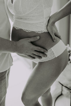 Image of husband holding belly of pregnant wife hands. Man kissing and hugging tummy at home. Loving Couple. Parenthood concept. Baby Shower. Family photo. Black and white photo.