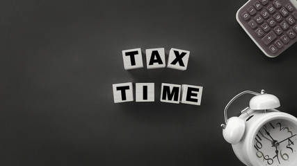 Tax-filling concept - Tax time words on wooden blocks with calculator and clock in vintage...