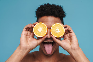 Photo of shirtless african american man making fun with orange