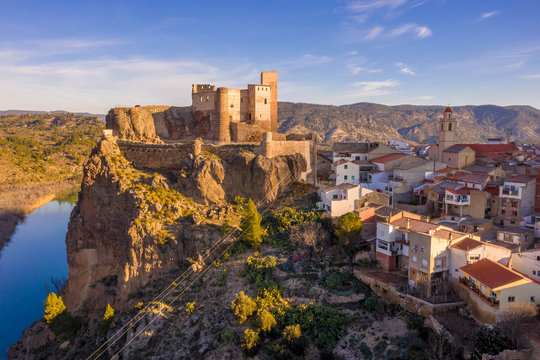 Aerial panoramic view of medieval partially restored Cofrentes castle above the Cabriel river in Spain with reflection and dramatic sky
