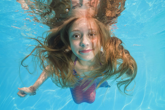 girl in a mermaid costume poses underwater in a pool. Young beautiful girl poses underwater in the pool.