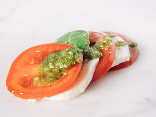 Healthy eating, Caprese salad . Vegetarian dinner. Fresh tomato sliced, mozzarella and basil. Mediterranean dieting. white plate