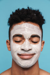 Photo of calm african american man in facial cosmetic mask smiling