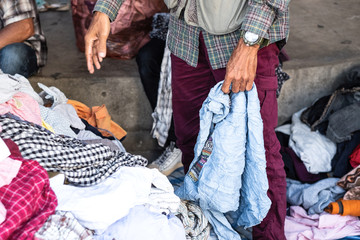 Thai man is choosing used second hand clothes at flea market in Thailand